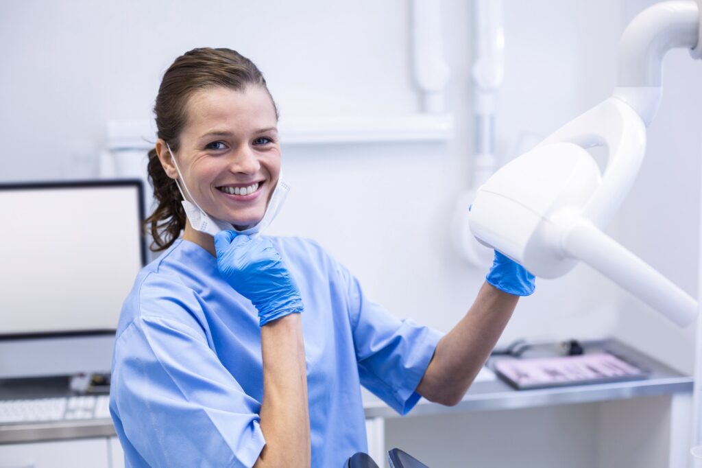 Smiling dental assistant adjusting light Smiling dental assistant adjusting light Smiling dental ass