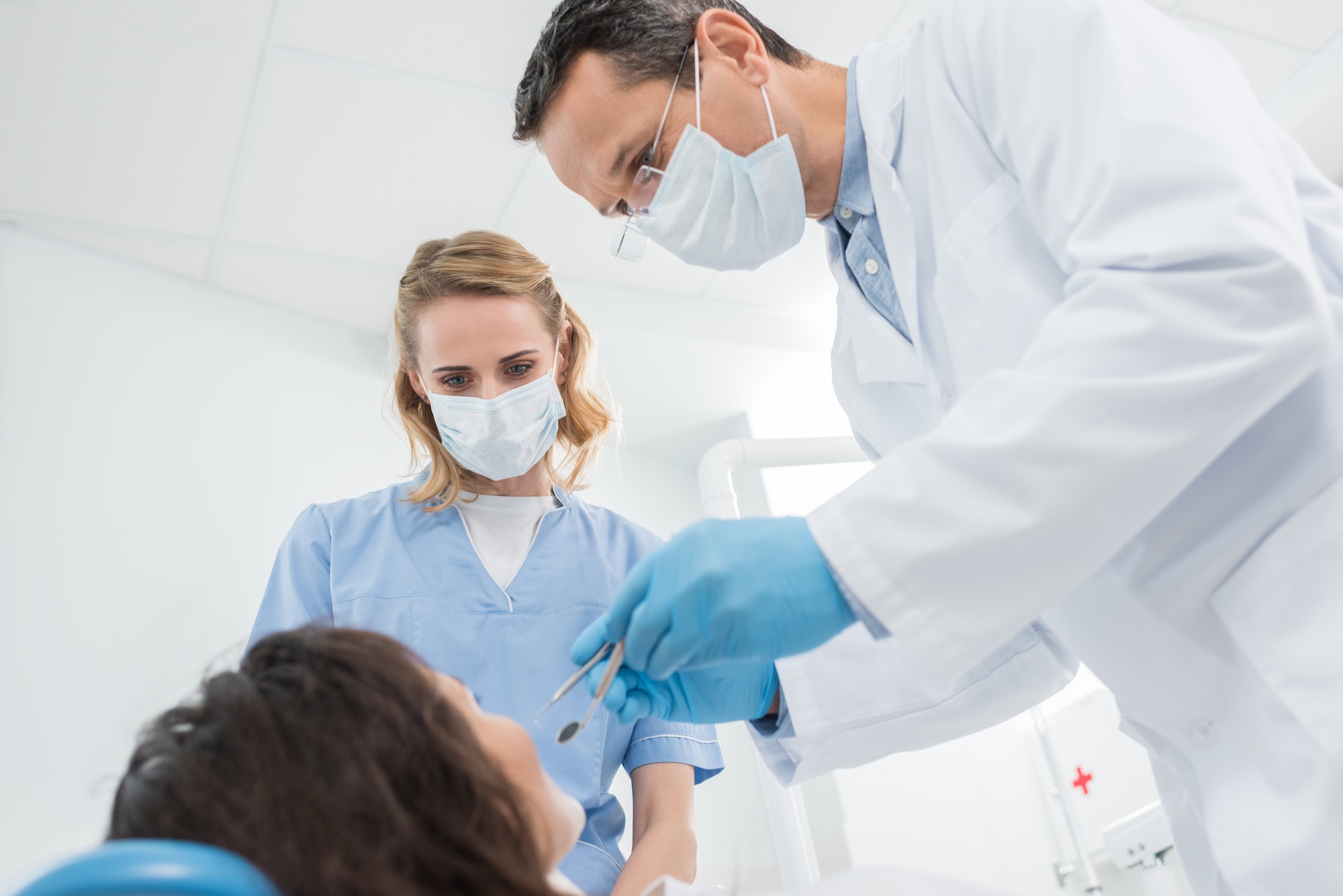 Male dentist and his female assistant checking patient in modern dental clinic